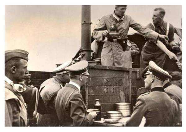 Adolf Hitler visiting a field kitchen (of a Luftwaffe unit); with his back to the camera, to the right Erwin Rommel......................