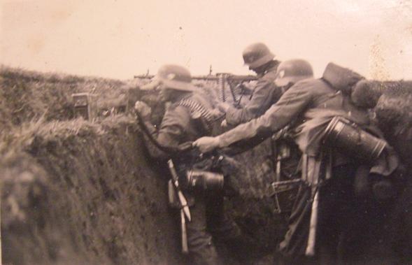 The crew of the machine gun MG 34 on bipod in action. It can be seen boxes of ammunition on the parapet of the trench and a band of munitions is placed over the shoulder of the soldier to the left of the gun.