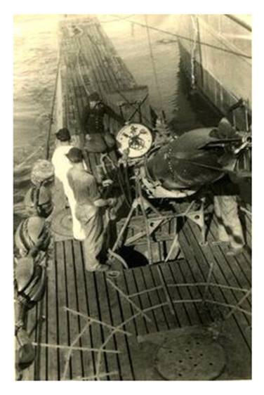 Loading a torpedo through the bow hatch into a Type VII (it seems); the deck gun has been removed........................................