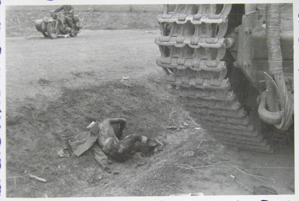 A half-charred crewman lies in the ditch beside his tank .........................................................