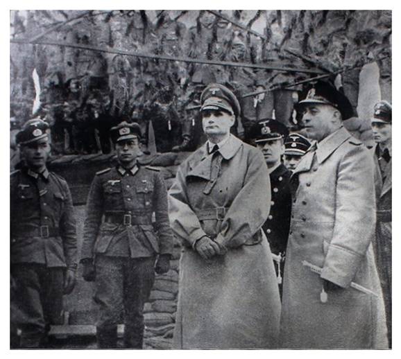Under the protection of the cammouflage net of an artillery position, the deputy of the Führer, Reichsminister Rudolf Hess, during a visit to the soldiers on the Canal front.............................................