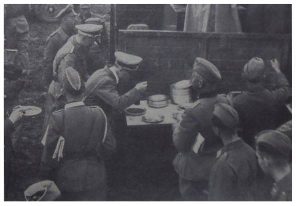The Führer shares lunch with his soldiers; General Reichenau (back to he camara) with a map under his arm and Himmler in the background?..............