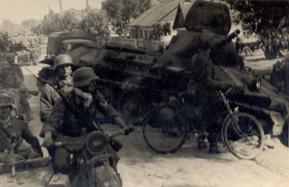 A German motorcyclist column rolling past a knocked out T-34 - somewhere in Russia.