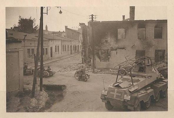 Light armored vehicles and motorcyclists inside a town ruined by the fighting; in the foreground a Sd Kfz 232 (8rad)  Funkwagen......................