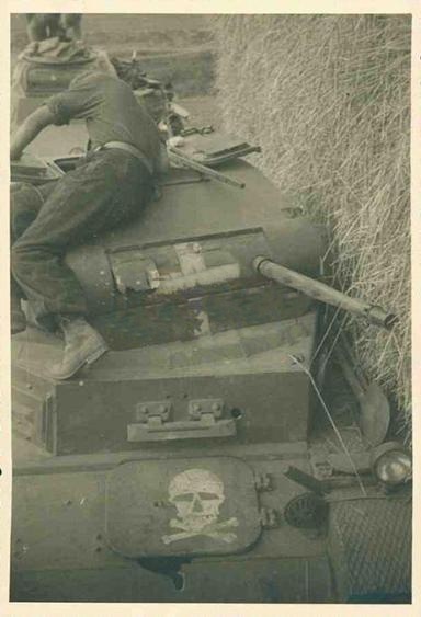 A Pz Kw II with the white cross (half removed) is seen at the center of the turret and a painting of a skull (Totenkopf) on the forward hatch; some damage also can be observed...............